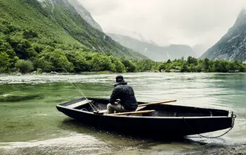 Laksefisker i båt ved elvebredden.